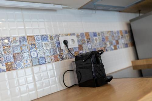 um saco preto sentado numa mesa ao lado de uma parede de azulejos em Casa Iringo Apartman By BLTN Balatonföldvár em Balatonföldvár
