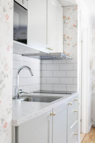 a kitchen with white cabinets and a sink at Orbaden Spa & Resort in Vallsta