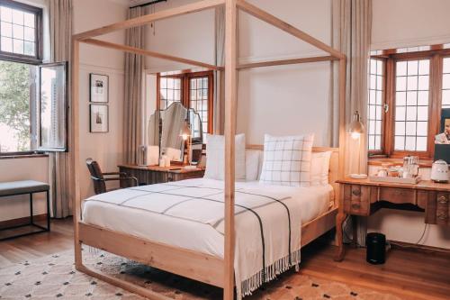 ein Schlafzimmer mit einem Himmelbett und einem Schreibtisch in der Unterkunft Sonnekus Boutique Hotel & Bistro in St James