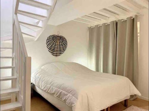 une chambre avec un lit blanc et un escalier dans l'établissement Loft/jardin et parking : Le Petit Clos Bourdet, à Honfleur