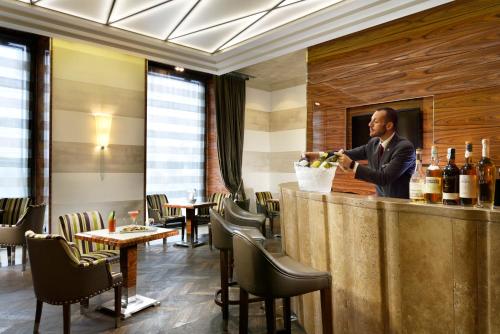 a man standing at a bar in a restaurant at UNA Hotels Decò Roma in Rome