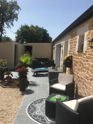 un patio avec des chaises et des tables ainsi qu'un mur en briques dans l'établissement l'intant zen naturiste, à Fresnay-en-Retz