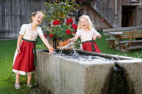 two little girls playing with water in a fountain at Ferienhof Weishäupl in Untergriesbach