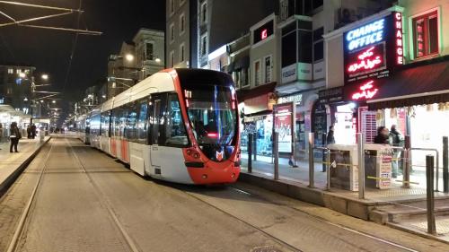 un tranvía rojo y blanco en una calle de la ciudad por la noche en Konut Wooden House en Estambul