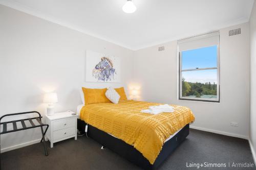 a white bedroom with a bed and a window at TC GARDENS 11 in Armidale