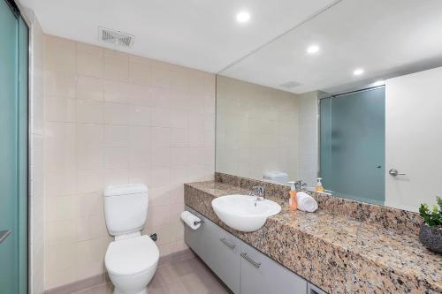 a bathroom with a toilet and a sink at Palm Cove Beachside Apartments - Sea and Mountain Views in Palm Cove