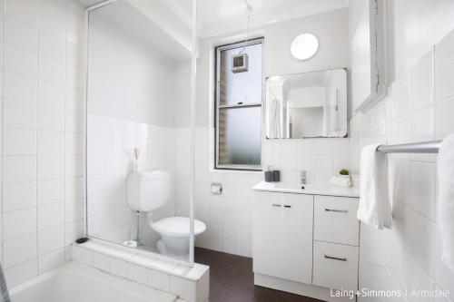 a white bathroom with a toilet and a sink at TC GARDENS 11 in Armidale