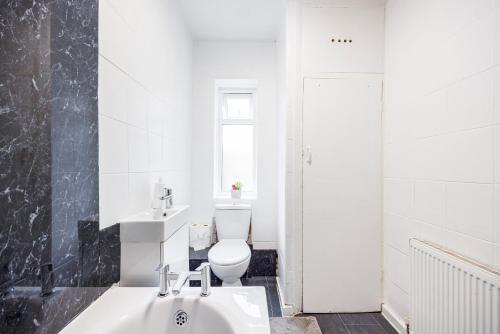 a white bathroom with a toilet and a sink at HeadsonBed- Croydon 4Bedrooms with Parking for the Larger groups in Hackbridge