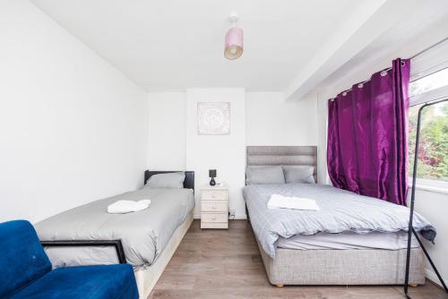 ein Schlafzimmer mit zwei Betten und einem Stuhl und einem Fenster in der Unterkunft HeadsonBed- Croydon 4Bedrooms with Parking for the Larger groups in Hackbridge