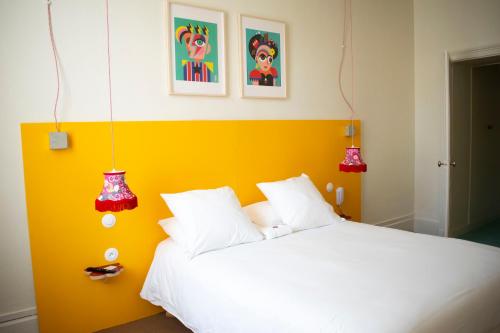 een slaapkamer met een wit bed en een gele muur bij Artyster Le Mans in Le Mans