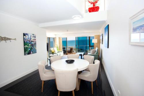 a dining room with a white table and chairs at Osprey Apartments in Mooloolaba