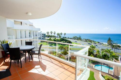 a balcony with a table and chairs and the ocean at Osprey Apartments in Mooloolaba