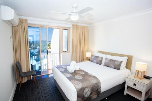 a hotel room with a large bed and a balcony at Osprey Apartments in Mooloolaba
