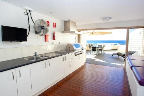 a kitchen with white cabinets and a view of the ocean at Osprey Apartments in Mooloolaba