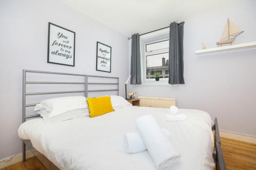 1 dormitorio con 1 cama blanca grande con almohadas amarillas en Beautiful 4 Bedroom Cottage - Free Parking en Edimburgo