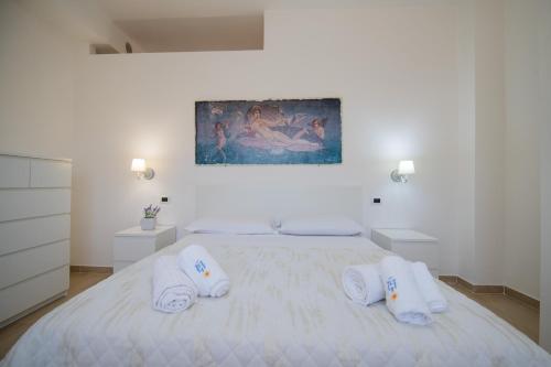 a white bedroom with a large bed with towels on it at Residence O'Sole Mio Pompei in Pompei