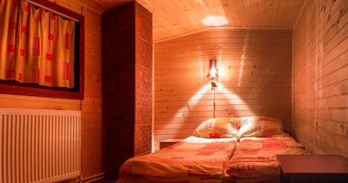 1 dormitorio con 1 cama en una habitación de madera en Szilvia Vendégház, en Izvoare