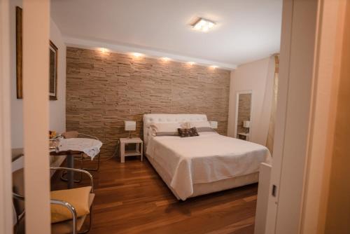 una camera con un letto bianco e un muro di mattoni di B&b Villa Maria Di Venere a Bari