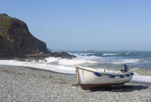 a small boat sitting on a beach near the ocean at Poppyfields in Germoe
