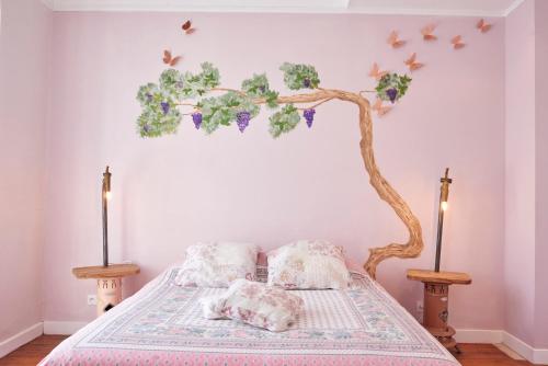 a bedroom with a bed with a tree and butterflies on the wall at Domaine du Prieuré Couvent & Presbytère in Carcassonne