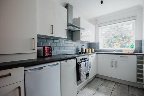 a kitchen with white cabinets and a window at Hullidays - Hymers Apartment in Hull