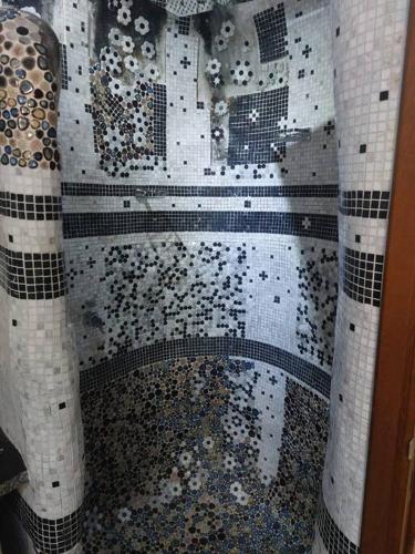 a shower with black and white tiled walls at apartment in Ajman for 4 persons near the sea in Ajman 