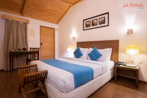 a bedroom with a large bed with blue and white pillows at Le Poshe, Kodaikanal in Kodaikānāl