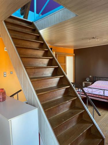 a wooden staircase in a room with a bed at « Le temps d’un instant » dépendance in Solre-le-Château