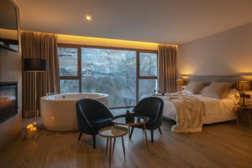 1 dormitorio con cama, bañera, cama y ventana en Almazara Suites en Alcalá del Júcar