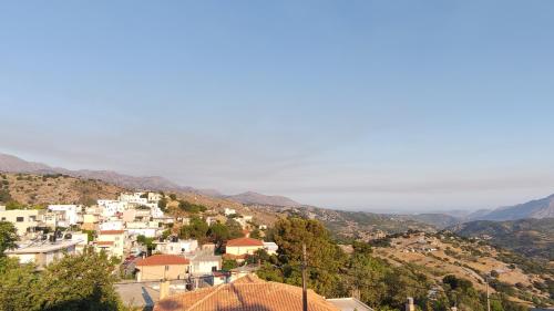 a group of white buildings on a hill with mountains at Melissa Apartments in Anogia