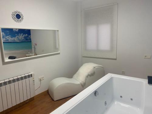 La salle de bains blanche est pourvue d'une chaise et d'une baignoire. dans l'établissement Casa Airen con jacuzzi, à Miguel Esteban