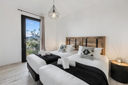 two white beds in a room with a window at DOMAINE OLMETA in Porticcio