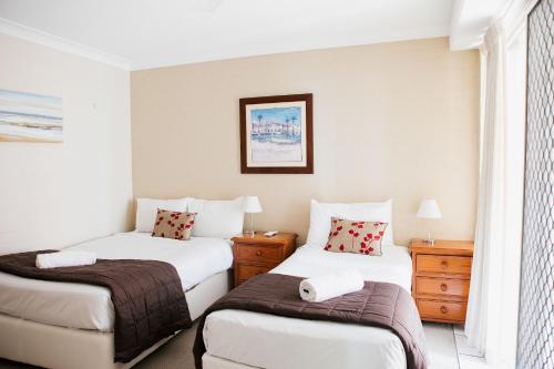 a hotel room with two beds and a window at Osprey Apartments in Mooloolaba
