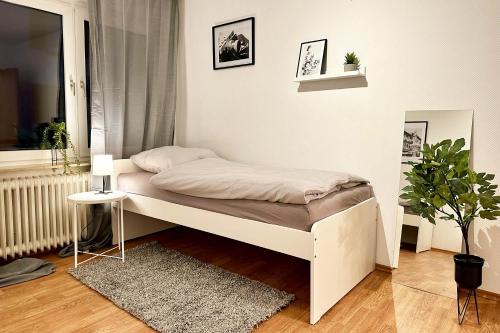 małą sypialnię z białym łóżkiem i rośliną w obiekcie Cozy Apartment in Wuppertal w mieście Wuppertal