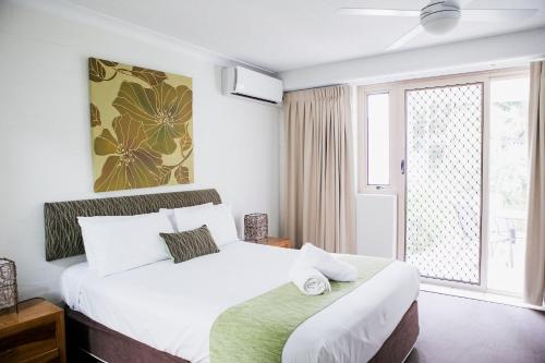 a bedroom with a bed and a large window at Osprey Apartments in Mooloolaba