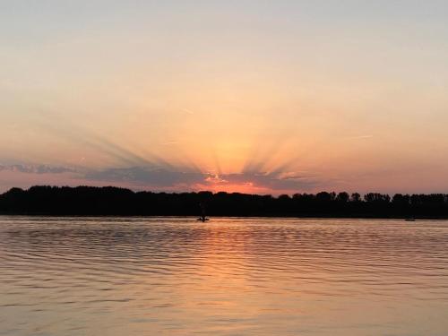 a sunset on a lake with a person in a boat at Strandparc Nulde in Putten