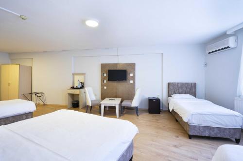 a room with four beds and a table and a desk at Hotel Libiza in Gebze