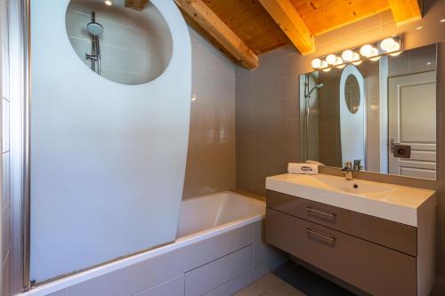 y baño con lavabo, bañera y espejo. en Chalet le Tremplin, en Chamonix-Mont-Blanc