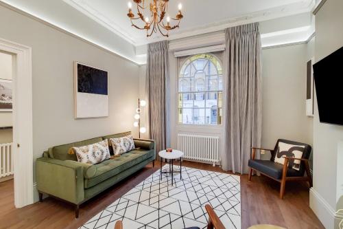 a living room with a green couch and a window at The Argyle Collection near Kings Cross St Pancras - by Short Stories London in London
