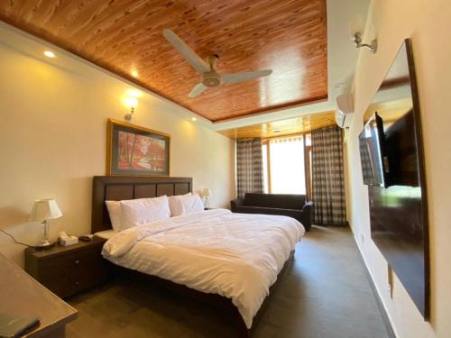 a bedroom with a large bed with a ceiling fan at Roomy Daastaan Hotel, Karimabad Hunza in Hunza