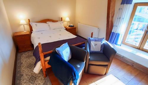 a bedroom with a bed and a chair and a window at La Cloue in Sainte-Marie-du-Bois