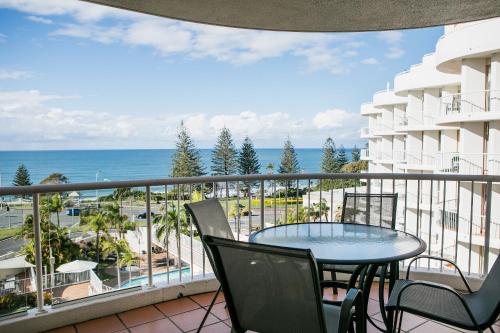 a balcony with a table and chairs and the ocean at Osprey Apartments in Mooloolaba