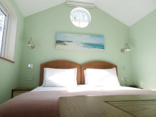 a bedroom with a bed with a wooden headboard and a window at The Lodge, Polgooth in St Austell