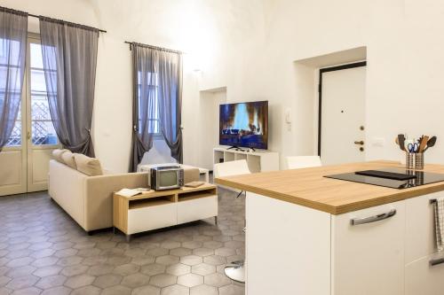 a kitchen and living room with a couch and a tv at Affittacamere Archivolto del Teatro in Albenga