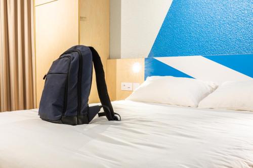 a backpack sitting on top of a bed at ibis budget Tours Sud in Chambray-lès-Tours