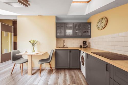 a kitchen with a table and chairs and a clock at Native Apartments Rakowicka 6 in Krakow