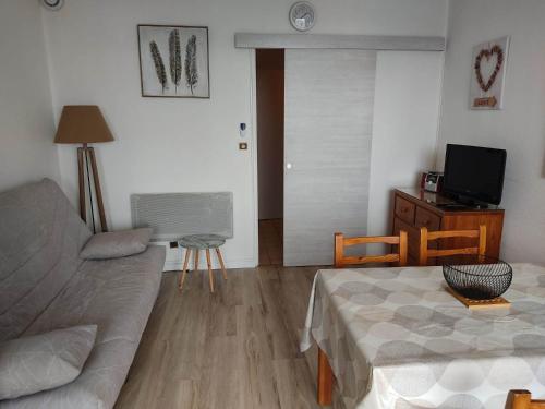 ein Wohnzimmer mit einem Sofa und einem TV in der Unterkunft Résidence les chênes blancs Appartement T2 in Gréoux-les-Bains
