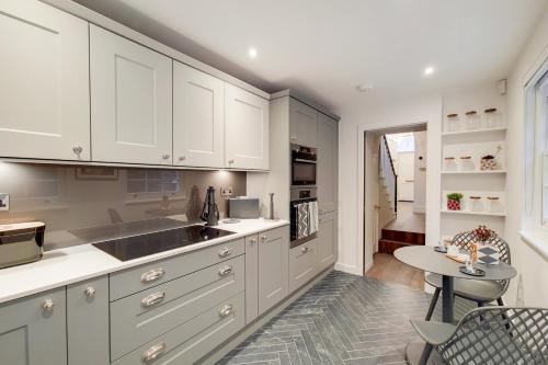 a kitchen with white cabinets and a table at The Argyle Collection near Kings Cross St Pancras - by Short Stories London in London