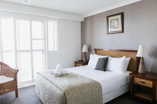a bedroom with a bed and a chair and a window at Osprey Apartments in Mooloolaba