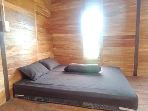 a bed in a room with wooden walls and a window at An Nur Homestay Bira Beach in Bira